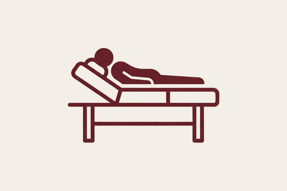 A minimalist line icon depicting a person lying down on a massage table, rendered in dark red on a light beige background.